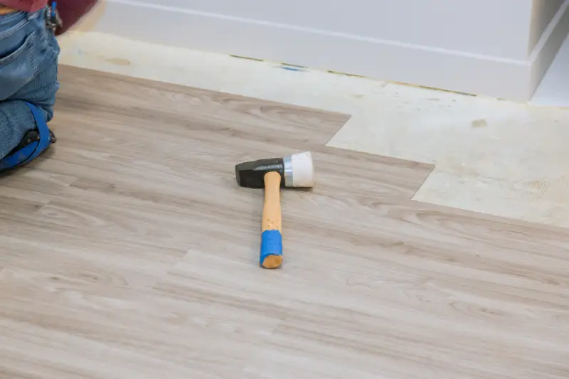 Hammer on laminate wood during floor installation.