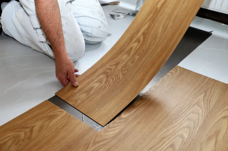 Handyman laying vinyl flooring.