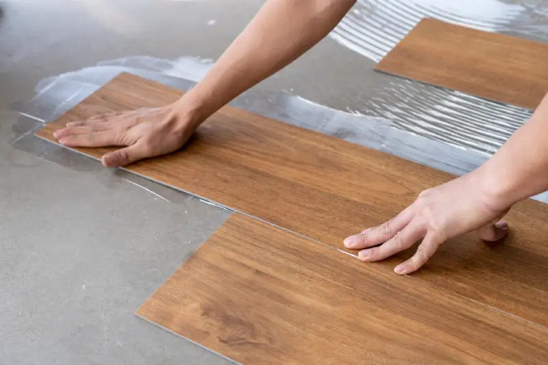 Handyman applying luxury vinyl flooring.