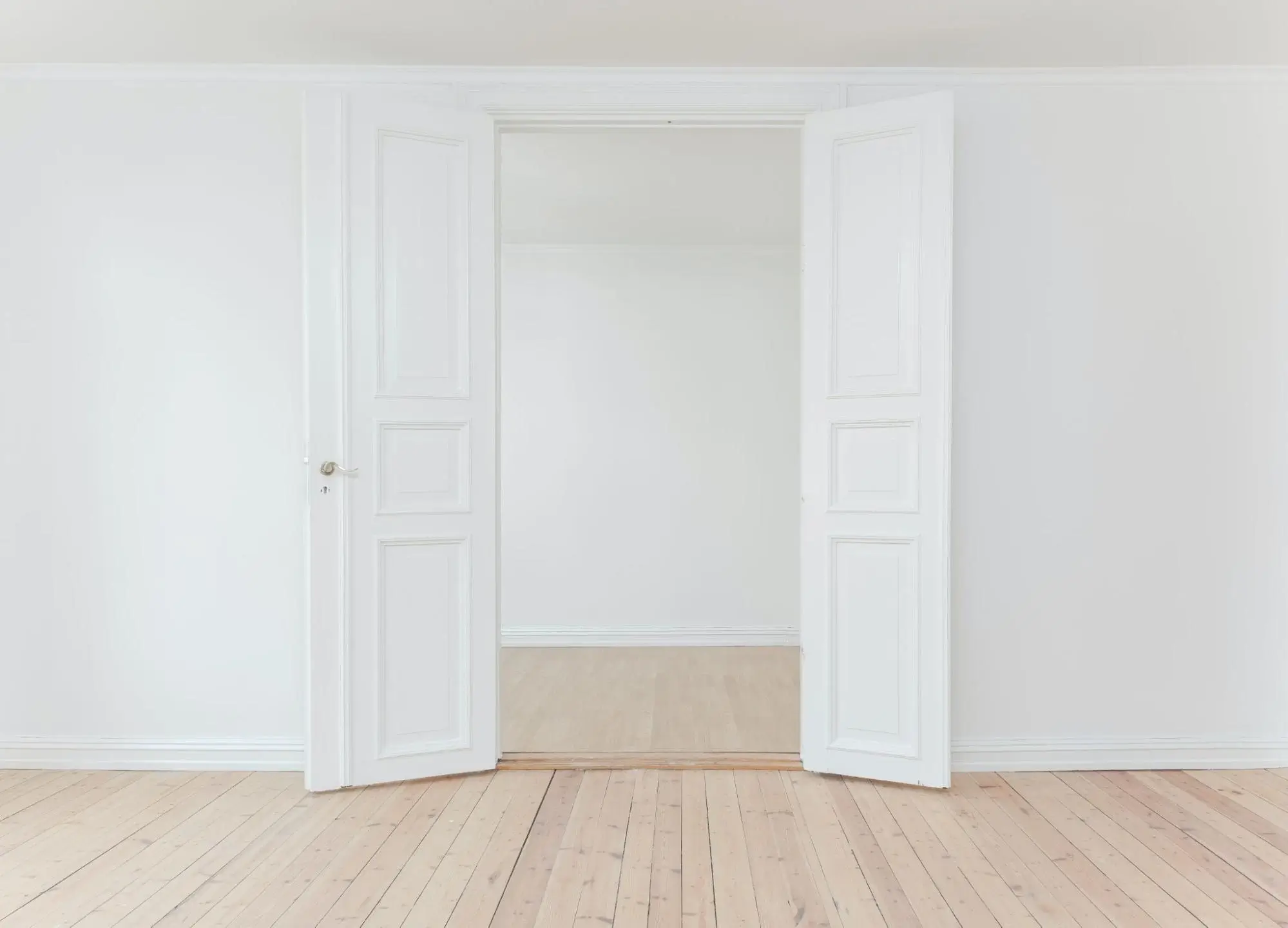 Open white doors and light wooden flooring.