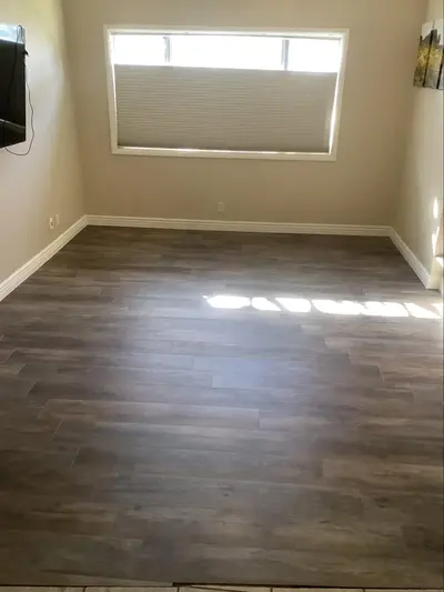 Dark hardwood flooring in empty sunlit room.