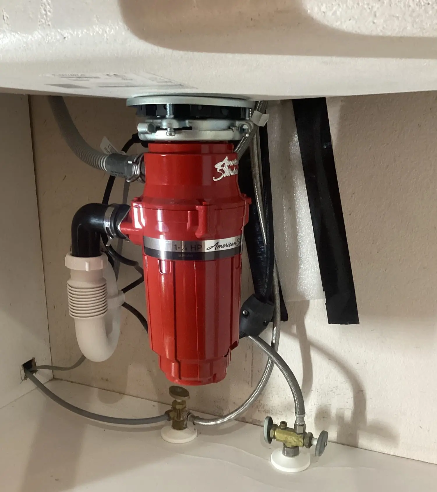 A newly installed red garbage disposal under a sink