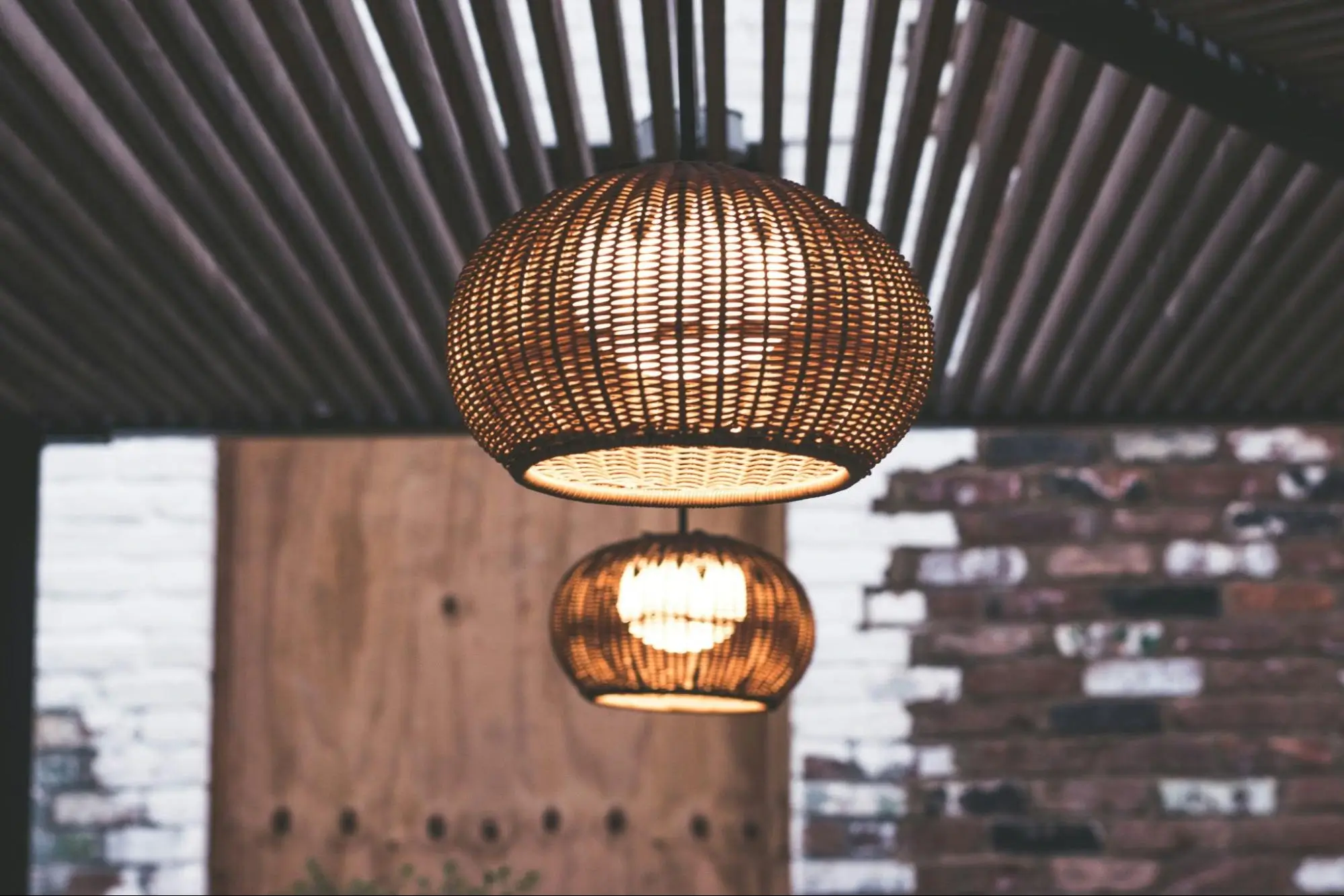 two woven pendant light fixtures hang from a patio ceiling.