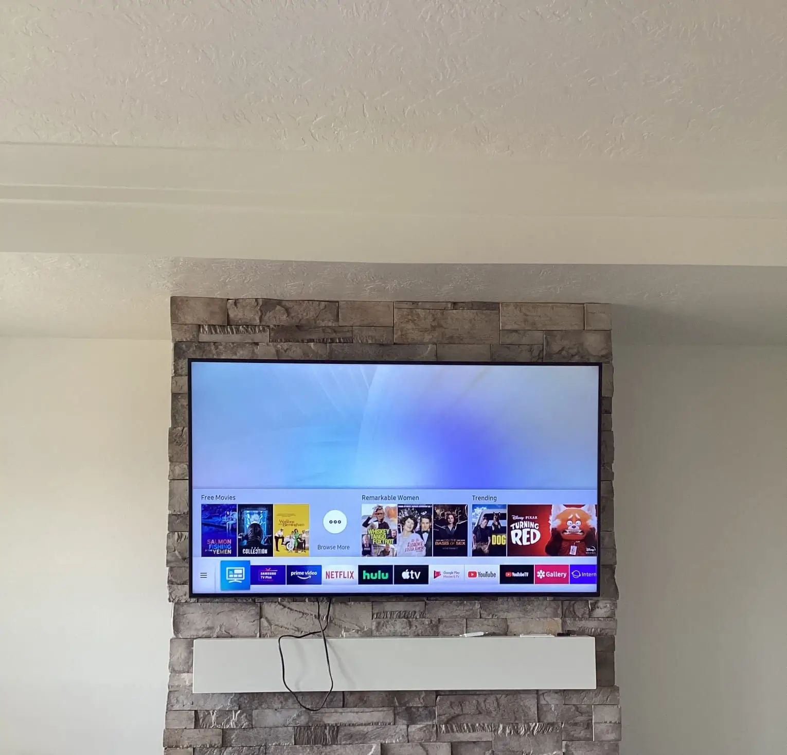 A client testimonial image of a large flat screen tv installed on faux brick.