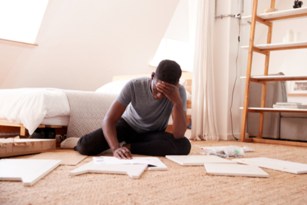 Homeowner frustrated while assembling IKEA furniture with instructions.