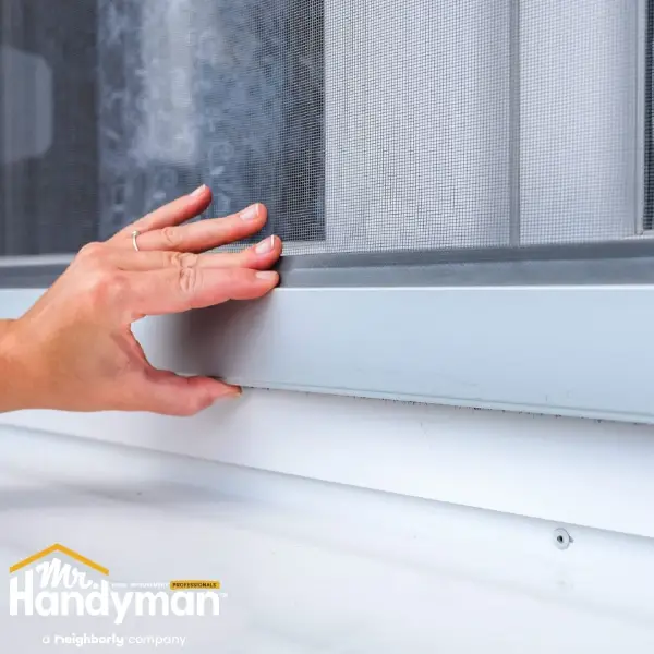 Hand checking window frame draft as part of holiday home safety preparation in Easton, PA.