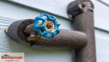 Insulated outdoor water faucet wrapped in foam pipe insulation to prevent freezing during cold weather, with Mr. Handyman logo in the corner.