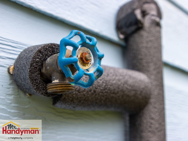 Insulated outdoor water faucet wrapped in foam pipe insulation to prevent freezing during cold weather, with Mr. Handyman logo in the corner.
