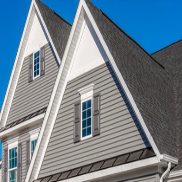 A close-up view of the gable and roof of a gray house.