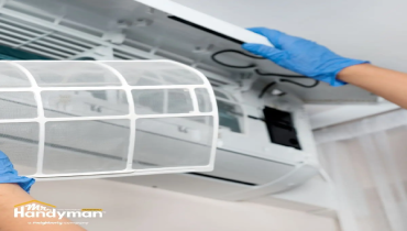 A person is removing an air conditioner filter.