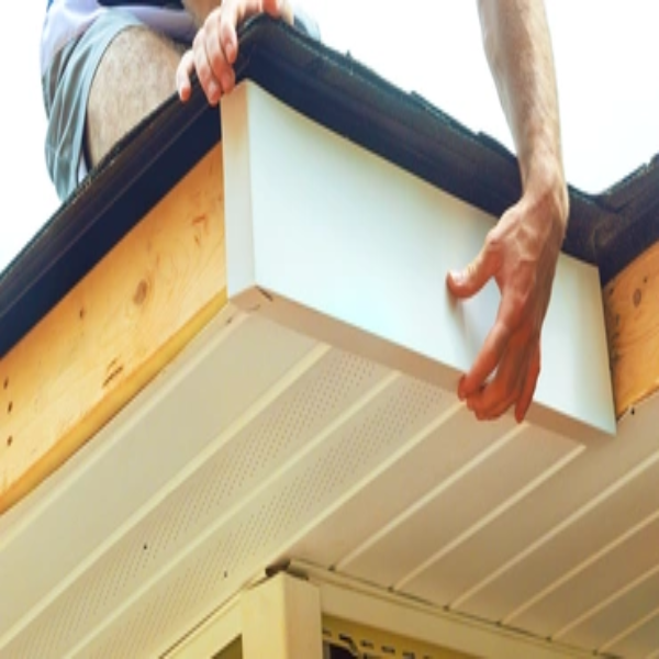 A person installing a piece of soffit on the edge of a roof.