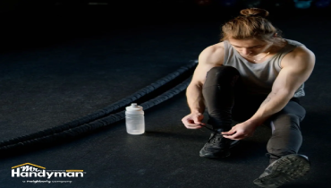 A man on the floor is engaged in tying his shoes.
