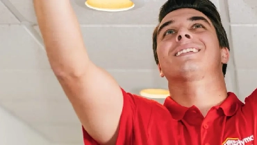 Mr. Handyman technician reaching up to the ceiling.