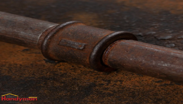 Close-up of a rusty metal pipe fitting on a corroded surface.