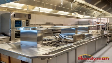 A modern commercial kitchen equipped with stainless steel countertops, multiple gas burners, and industrial ventilation hoods.