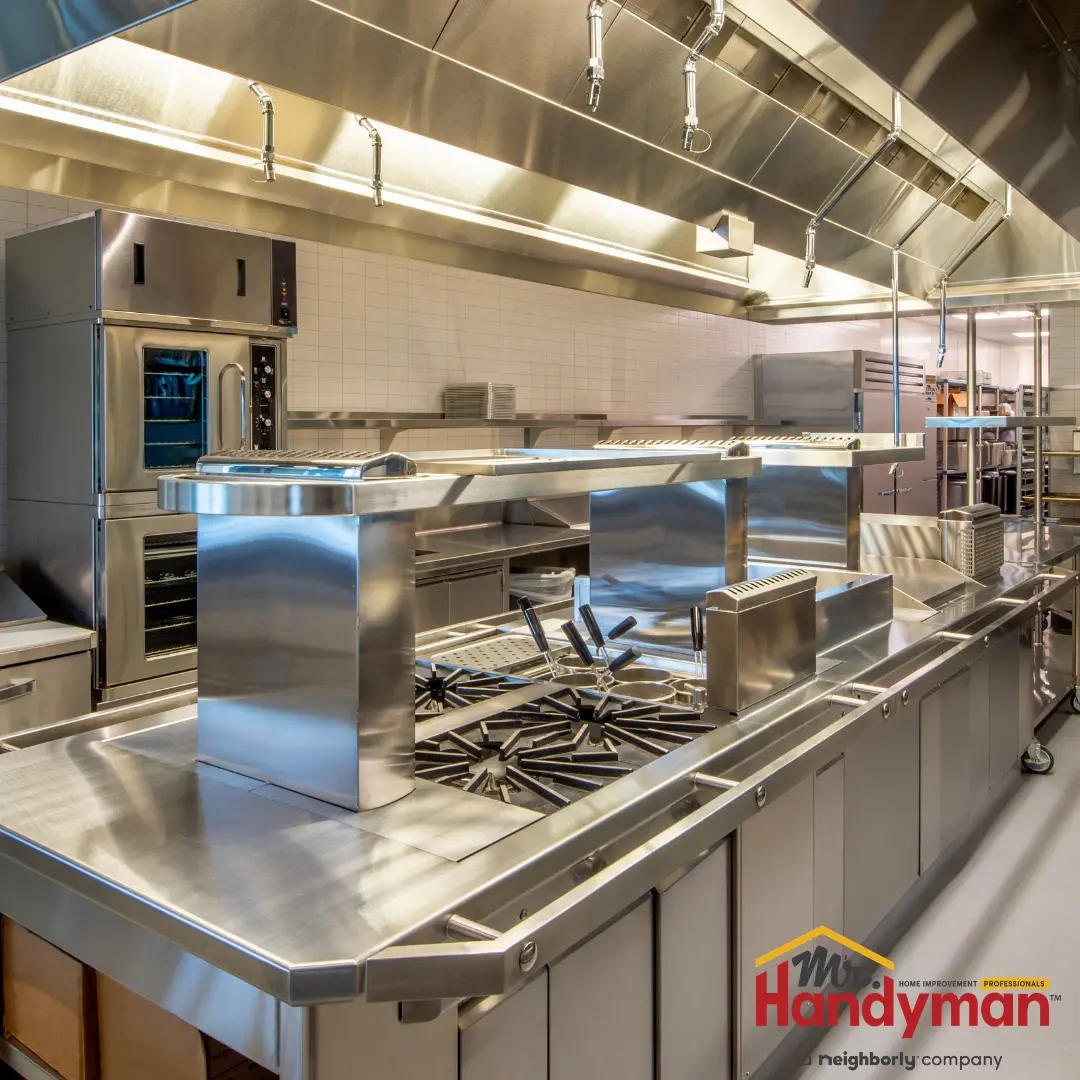A professional stainless steel commercial kitchen featuring a large central stove.