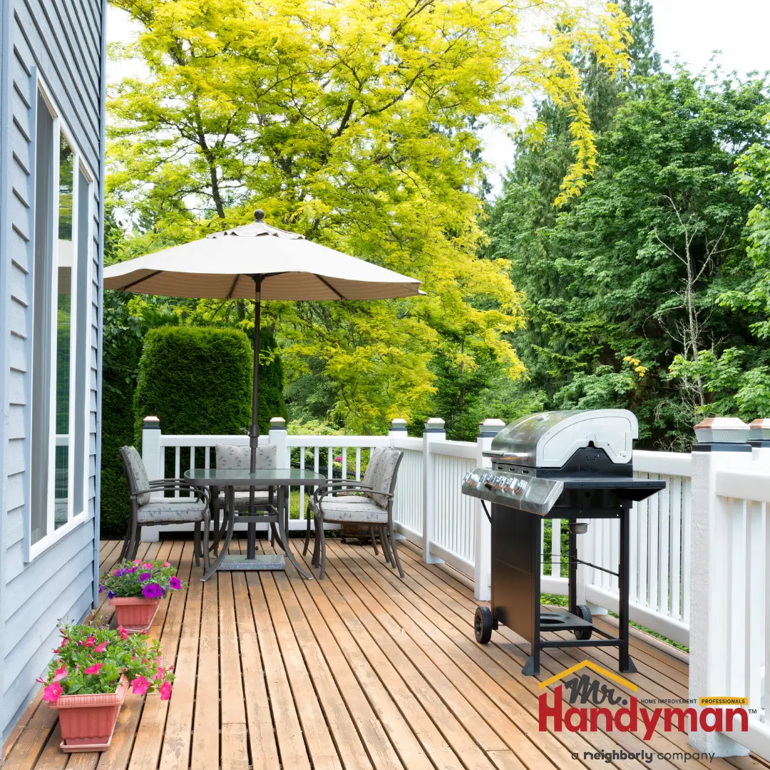 A Mr Handyman-branded outdoor deck featuring a wooden floor, white railing, and a barbecue grill.