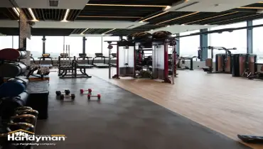 Mr. Handyman technician professionally installing large gym mirrors on a fitness facility wall in South Bend Northern Indiana