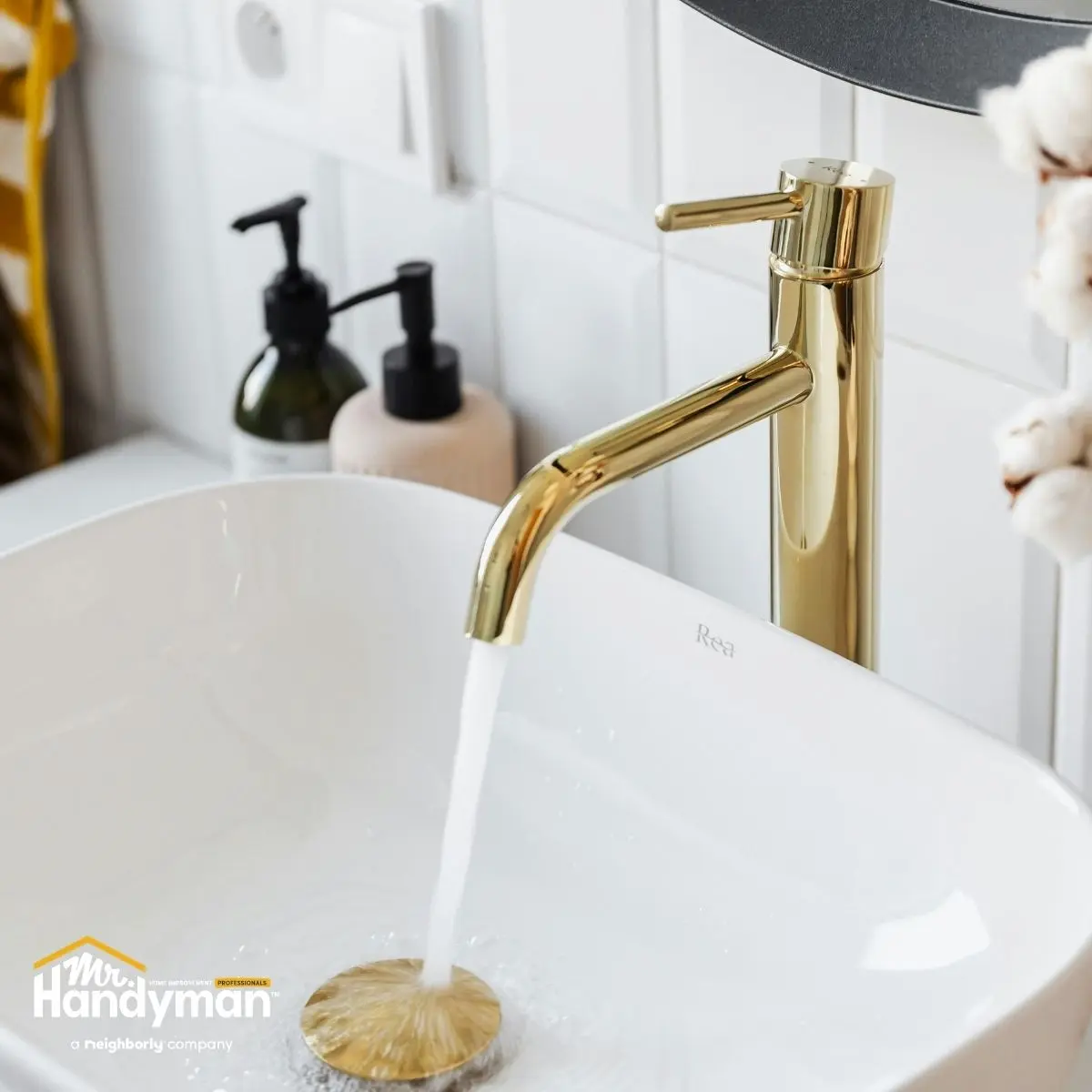 Gold faucet with water flowing into a modern white vessel sink.