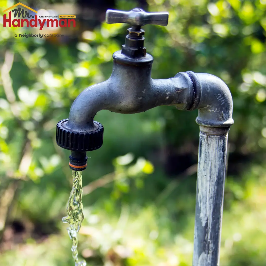 A close-up of a garden faucet with water dripping from the spout.
