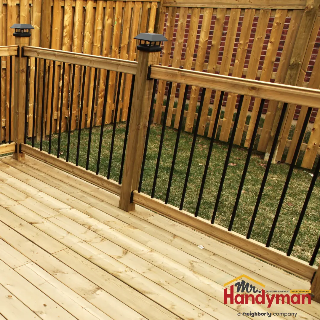 A wooden deck with railings, featuring black metal bars and decorative lighting fixtures.