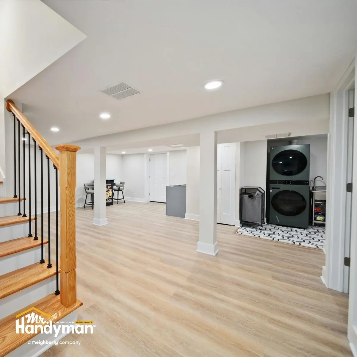 modern basement with light wood flooring a staircase with wooden railing a laundry area.