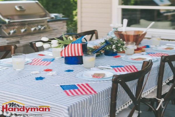 A backyard table set for a celebration, decorated with American flags, star-shaped ornaments, and fresh flowers.