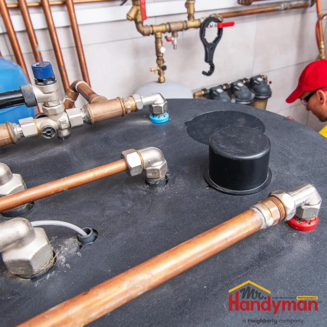 A hot water tank with copper piping, pressure relief valves, and a black pressure relief cap in place.