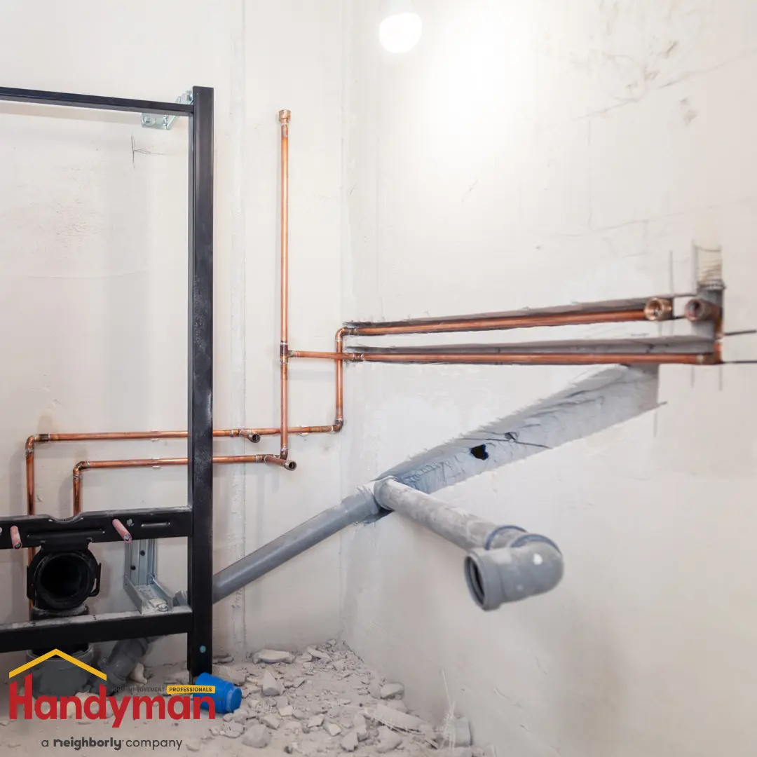 A section of plumbing work in progress, featuring copper water supply lines, gray PVC drainage pipes, and a partially installed toilet frame.