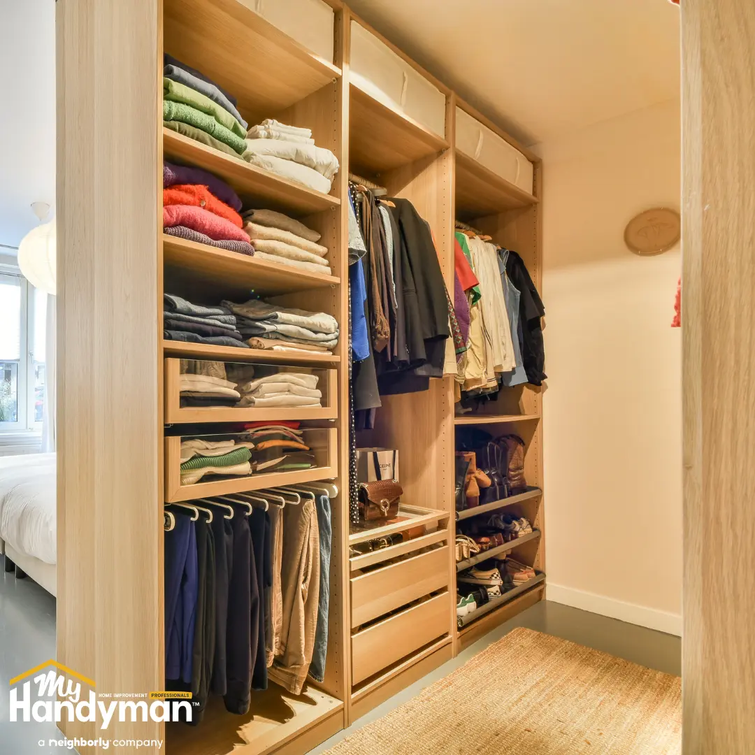 Organized walk-in closet with wooden shelves, folded clothes.