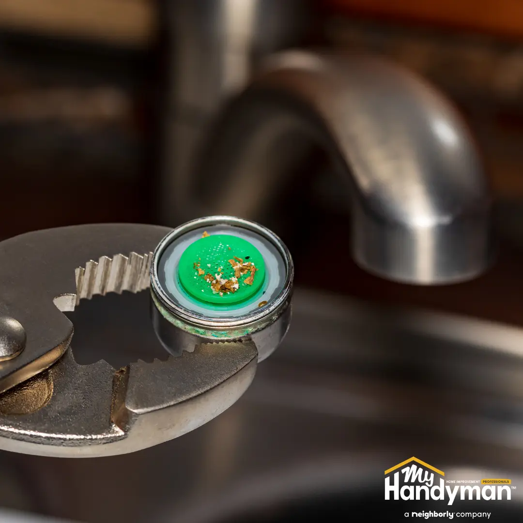 Adjustable wrench holding a corroded faucet aerator.