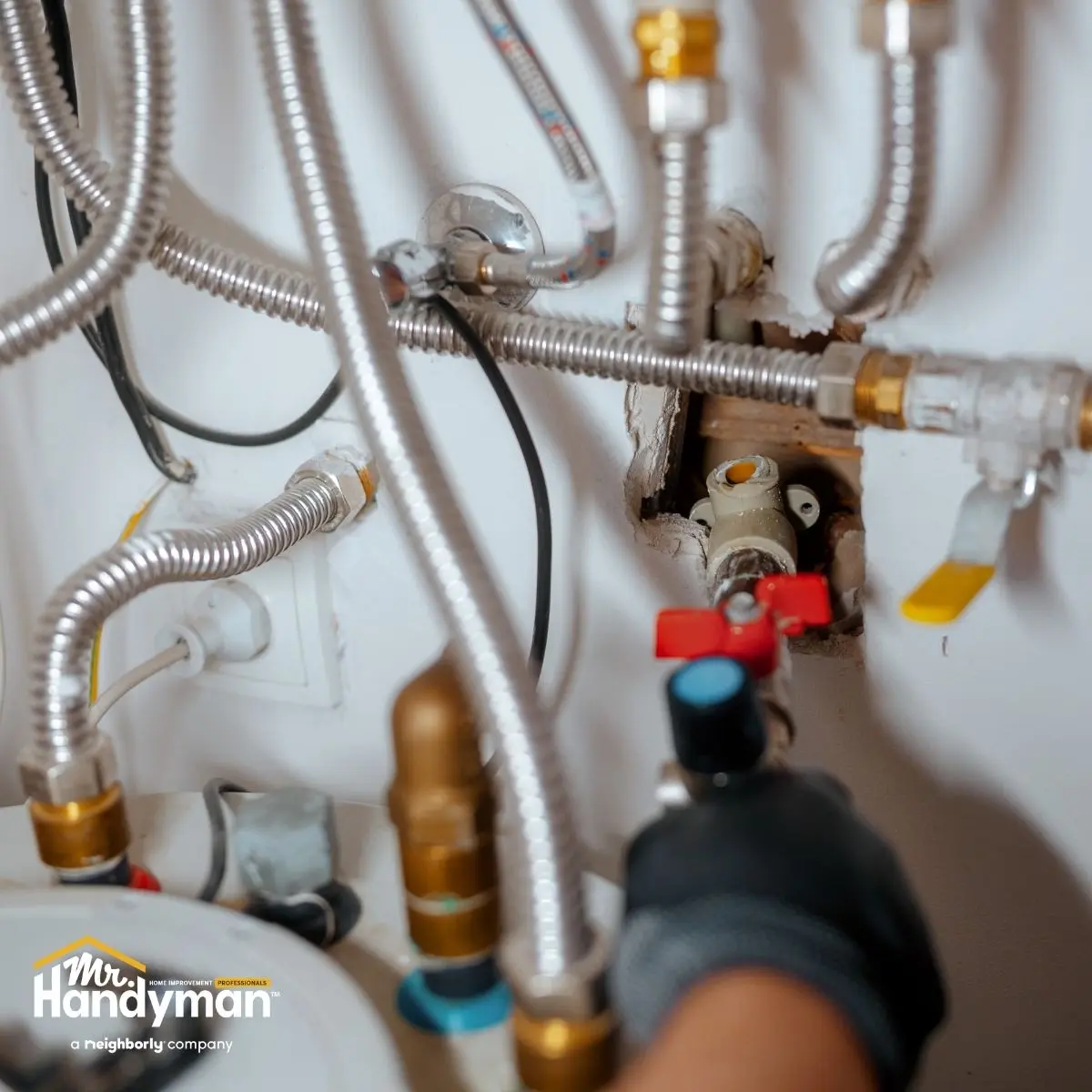 Close-up of a hand with a tool working on metal plumbing pipes and valves.