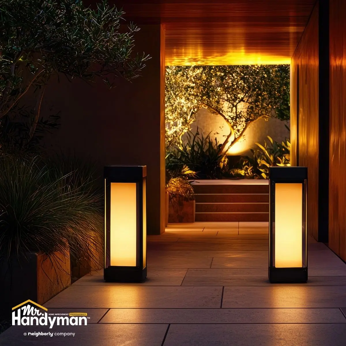 Modern outdoor walkway with two illuminated bollard lights.