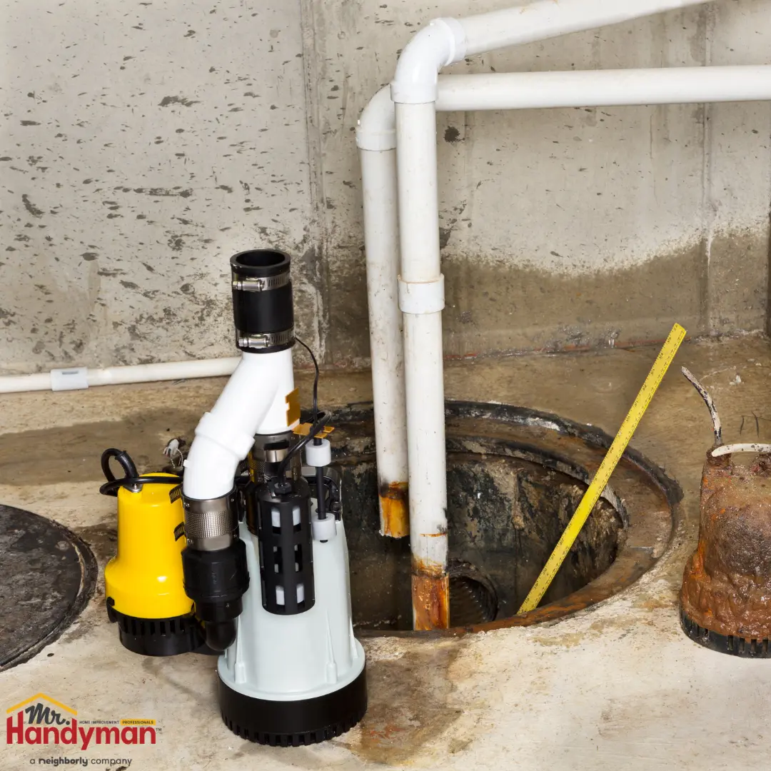A new yellow and grey sump pump sits on a concrete floor next to an open pit.