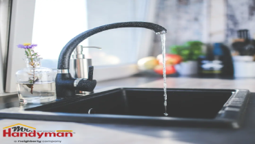A modern kitchen sink with a tall-curved faucet running water.