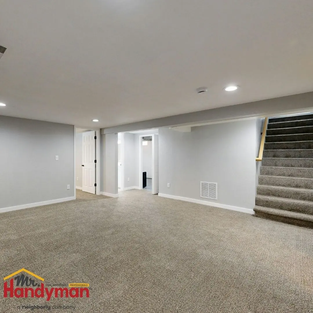Finished basement with gray walls, carpeted floor, recessed lighting, multiple doorways, and a staircase leading upstairs.