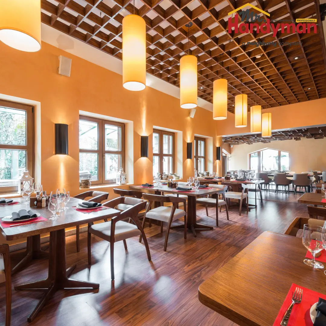 Elegant restaurant dining room featuring orange walls and a row of large cylindrical pendant lights.