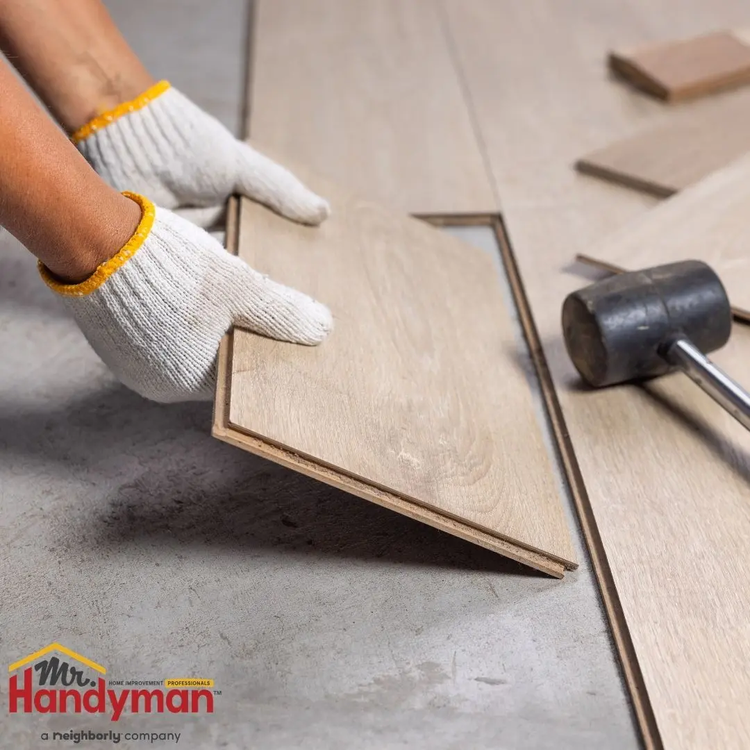 Person installing wood laminate flooring planks.