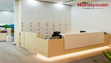 A reception area, featuring a modern reception desk with integrated lighting and a wall of lockable storage cubbies.