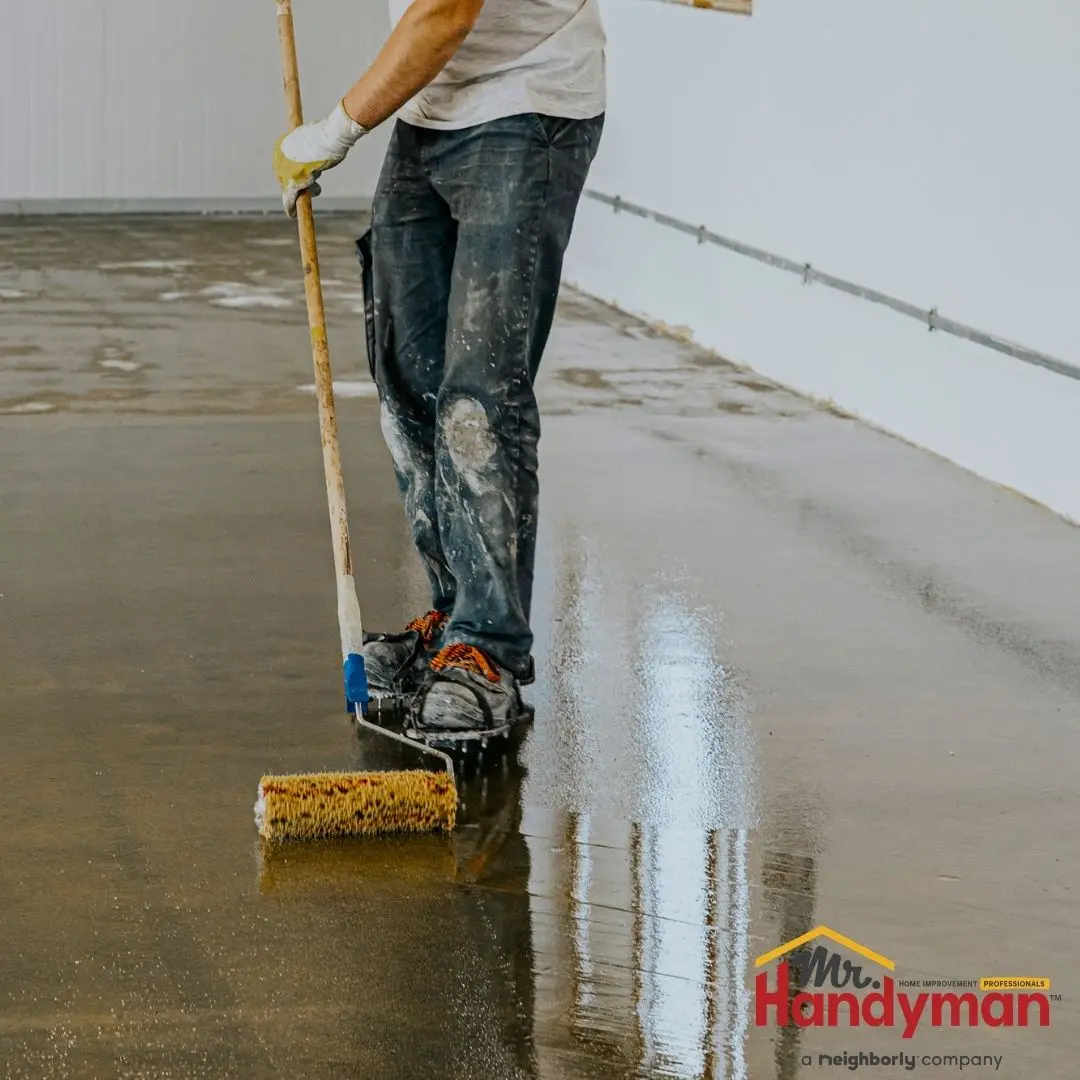 A man standing on a wet floor and using a broom to clean it.