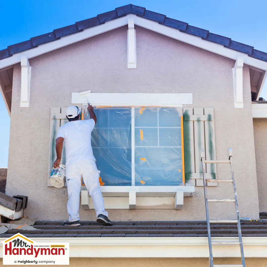 Painter painting the trim around a second-story window.