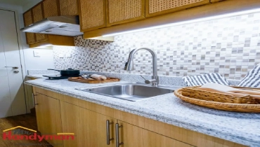 Modern kitchen with granite countertop, stainless steel sink, and stylish backsplash.