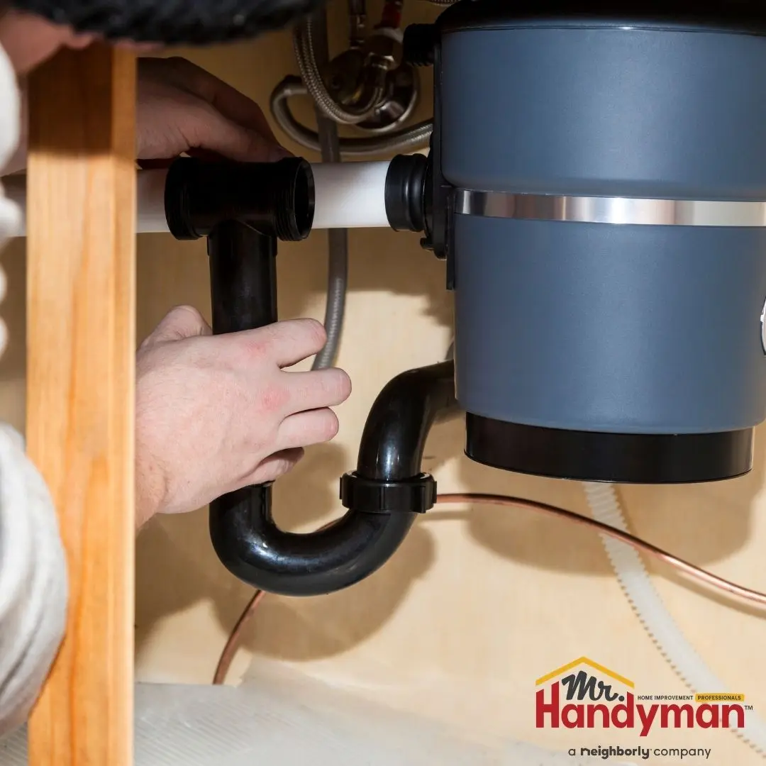 Mr. Handyman technician inspecting a garbage disposal under a kitchen sink in a Charleston, South Carolina home.