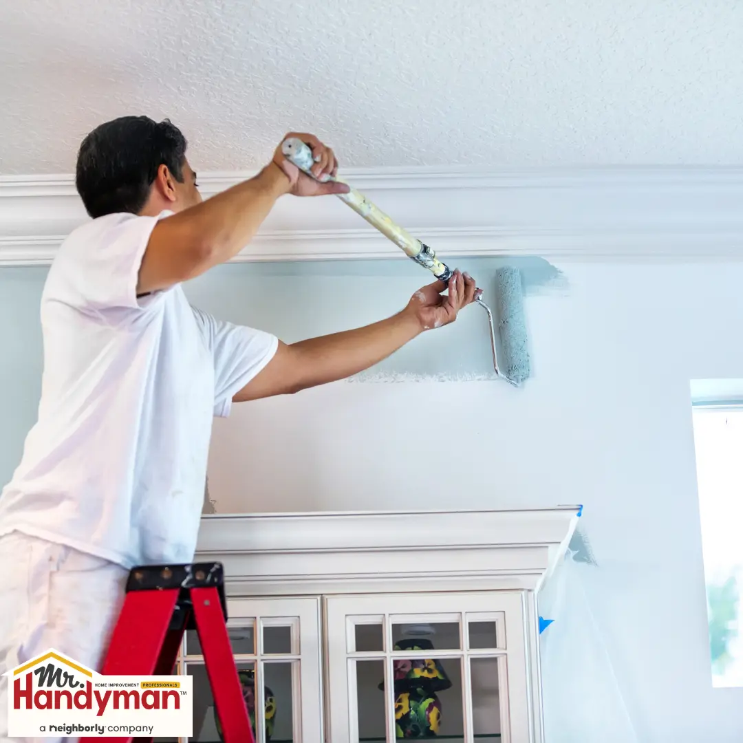handyman painting an interior wall during a home refresh
