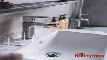 Handyman technician installing a new brushed nickel bathroom faucet