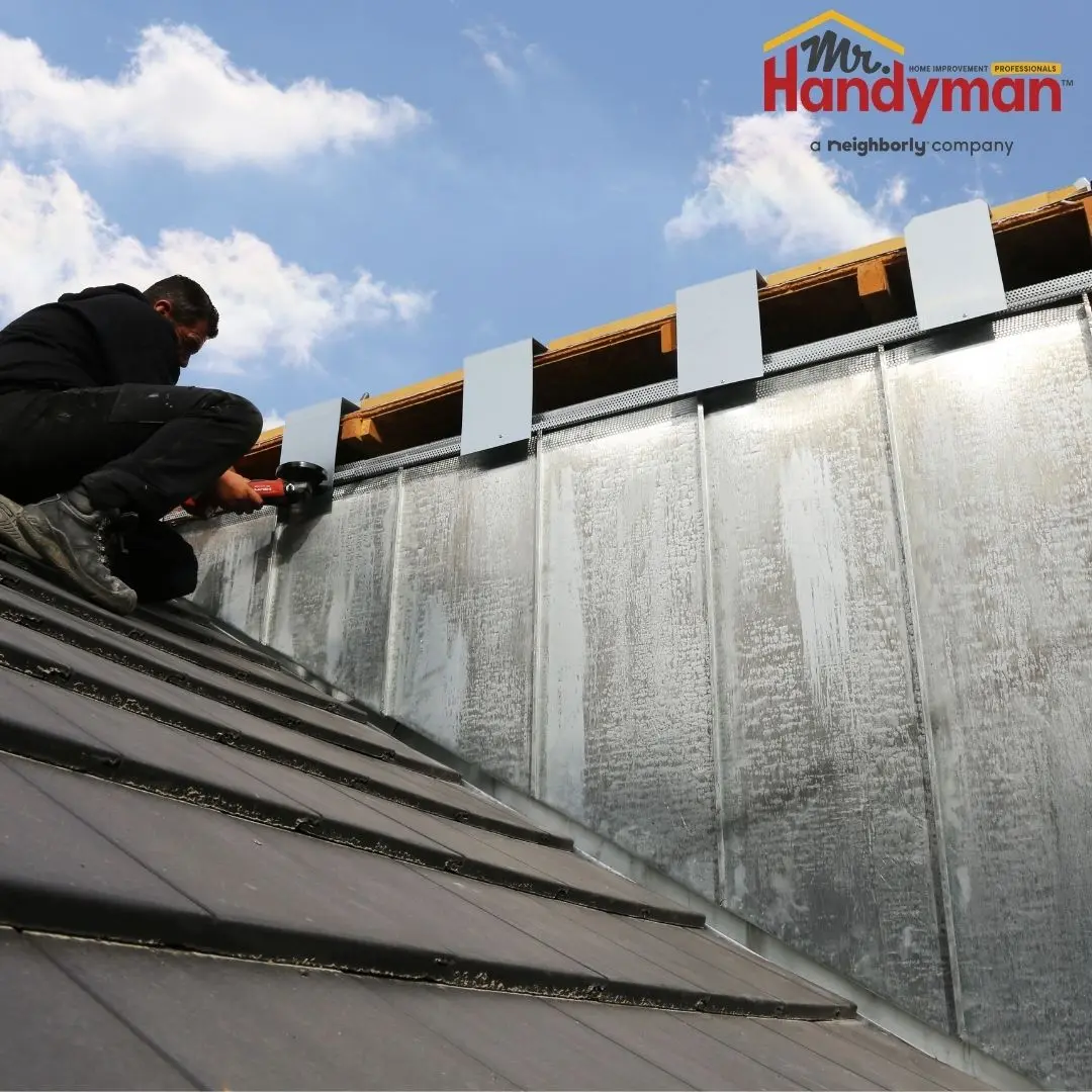 A person repairs a building's roof with metal siding.