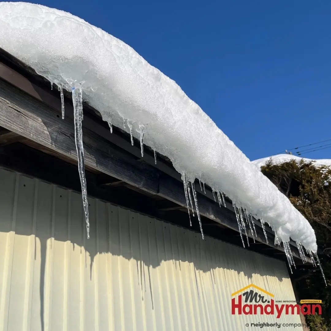 Snow and icicles hanging from a wooden roof.