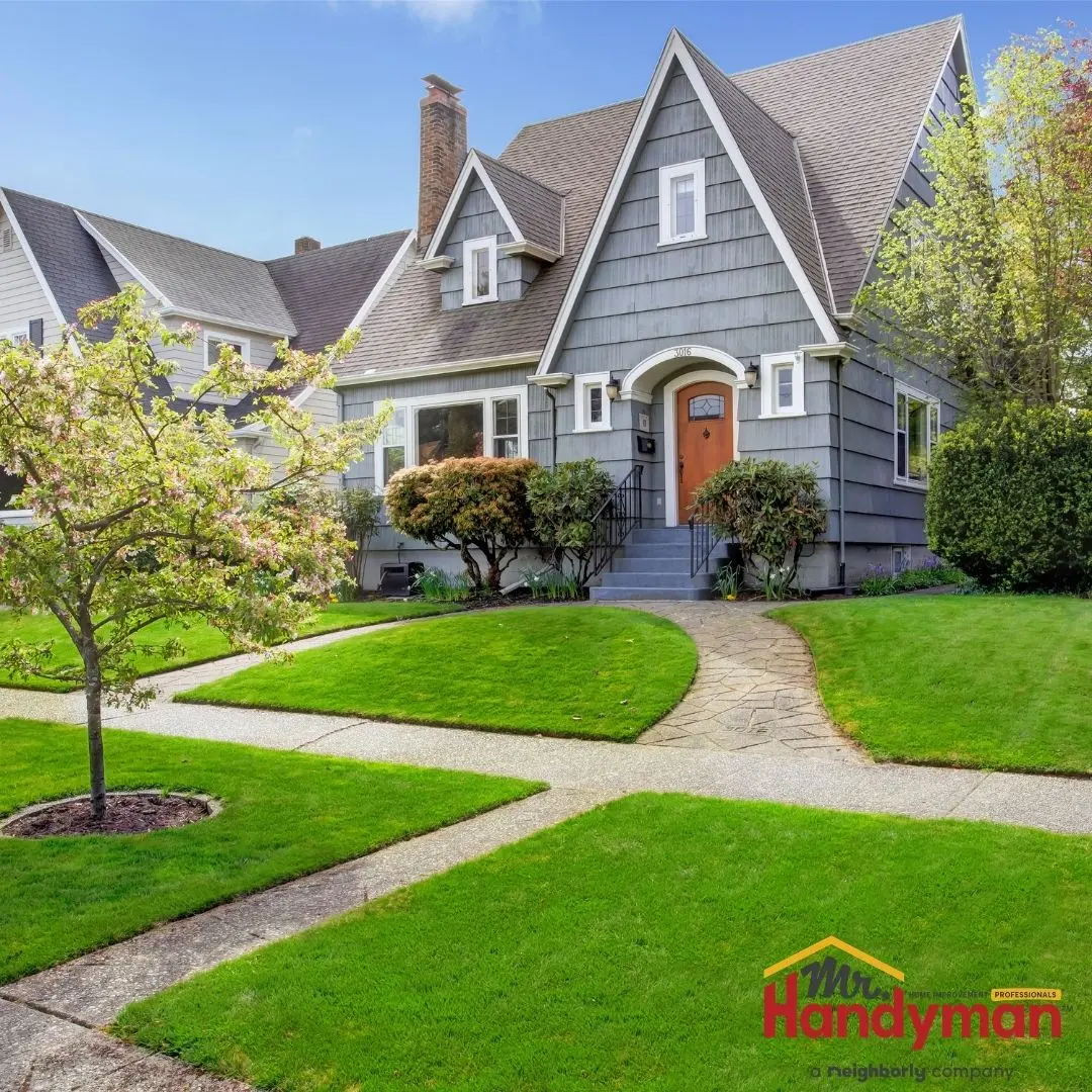 The front view of a well-kept suburban home with a neatly manicured lawn, stone walkway, and a bright orange front door.
