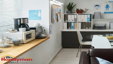A modern home office corner featuring a coffee station, microwave, and neatly organized filing cabinets.