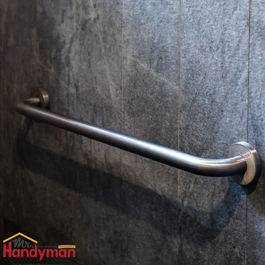 metal grab bar mounted on dark gray tiled wall